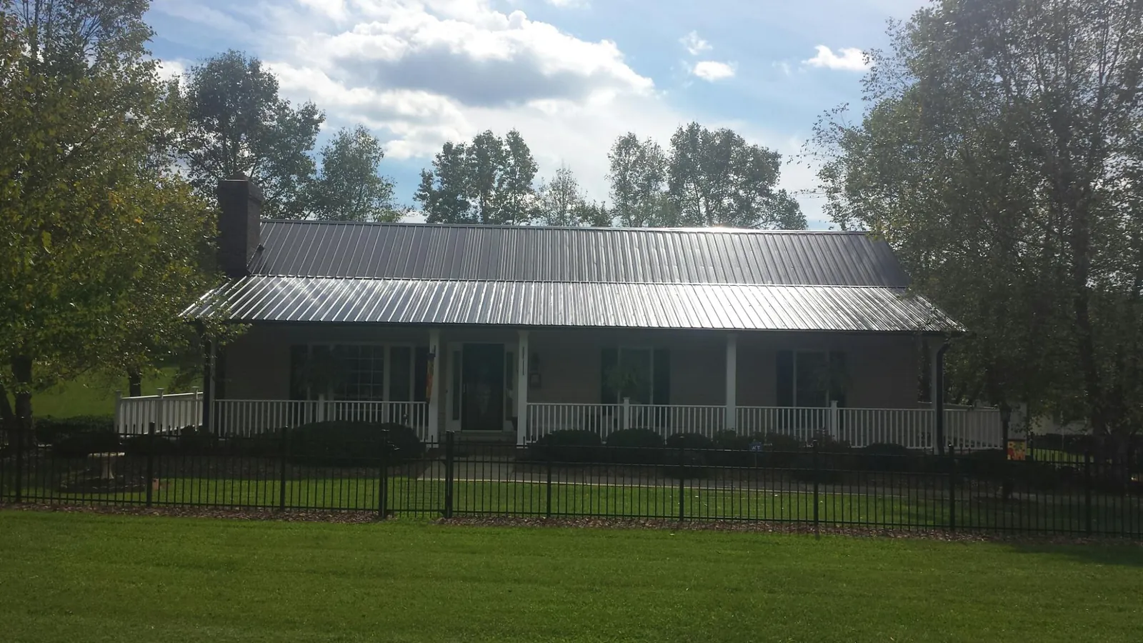 Gray metal roof on a brick ranch with a full width front porch — Gutter Guard Installation work by our crew in Georgetown